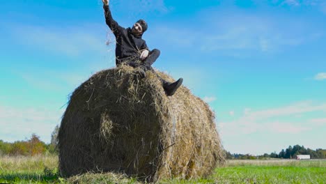 man sitting on a hay bale in a field