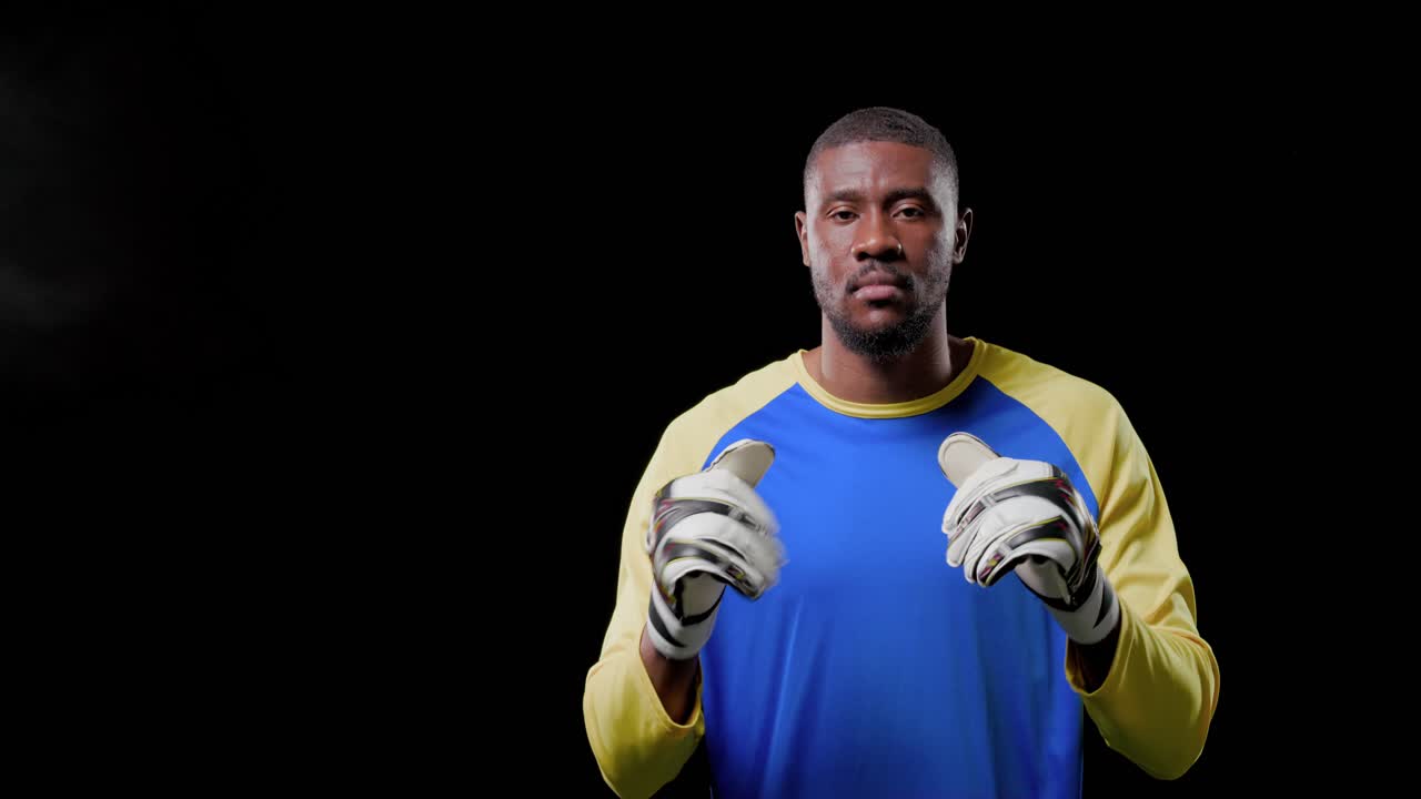 Uomo di mezza età che allaccia i guanti da portiere, con indosso una maglia blu-gialla in studio, che testa la presa da partita
