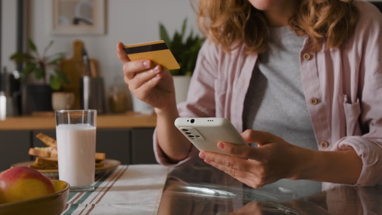 Woman using phone and credit card during breakfast