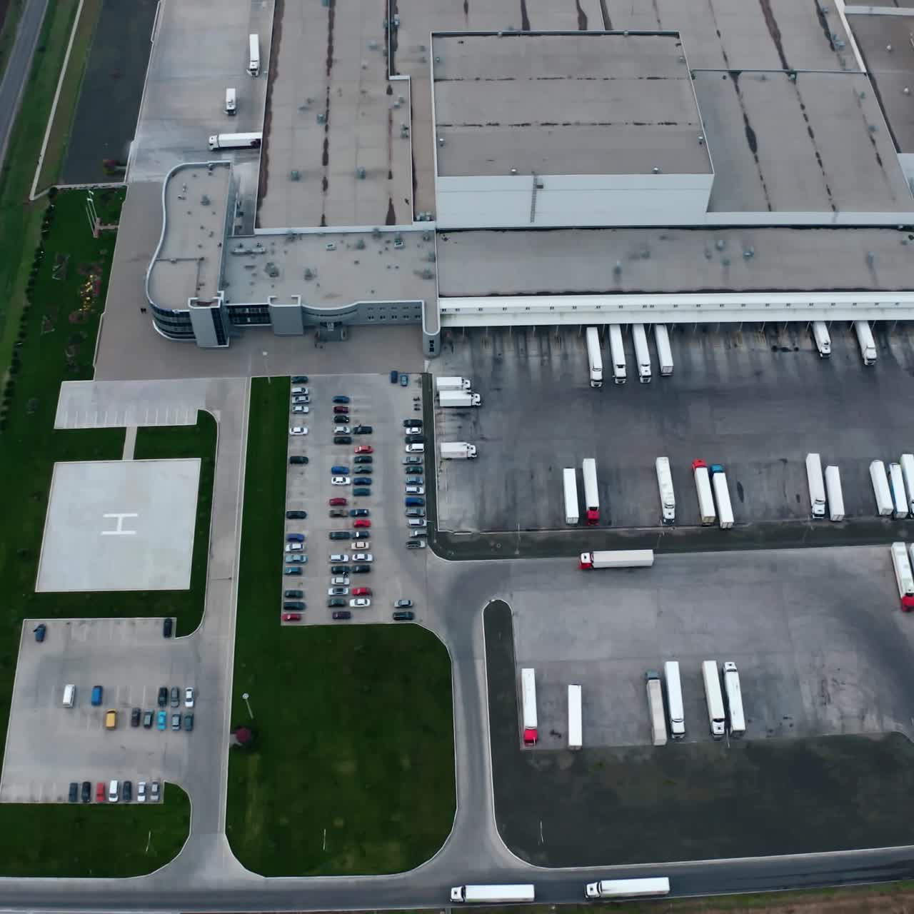 Industrial zone on the field. Roofs of modern plant with parking places. White trucks and cars on industrial territory on field. Aerial view.