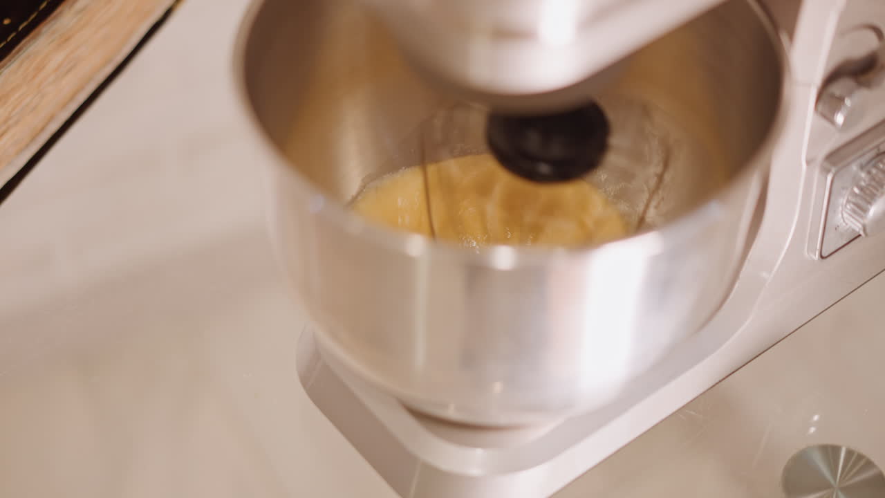 Mixer blends seasonal. Cinnamon dust floats over golden mixture. Festive flavors develop during holiday baking preparations. Overhead mixer stirs pumpkin filling as cinnamon dust floats in motion