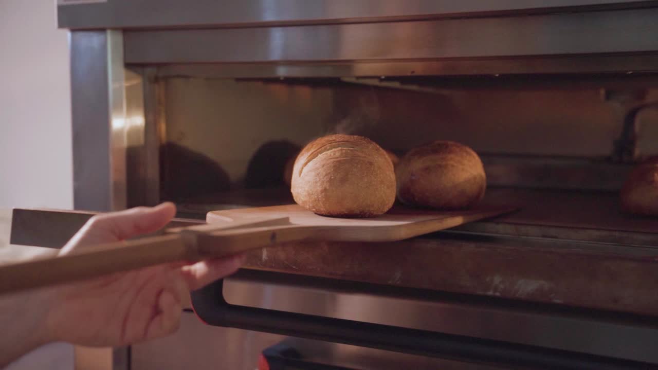 Freshly baked bread being removed from an industrial oven, slow-motion shot, emphasis on texture
