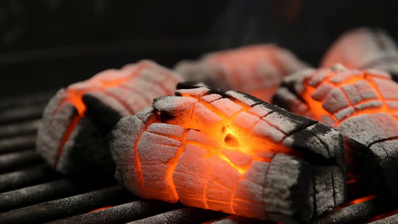 Glowing Charcoal On Grill Closeup Showing Orange Embers, Cracked Briquettes Nestled On Metal Grate, Thin Wisps