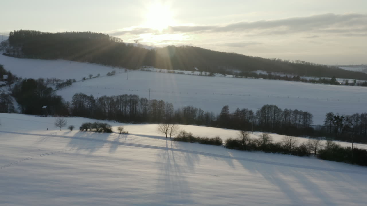 toma aérea ascendente del campo agrícola congelado y el bosque, paisaje invernal al amanecer