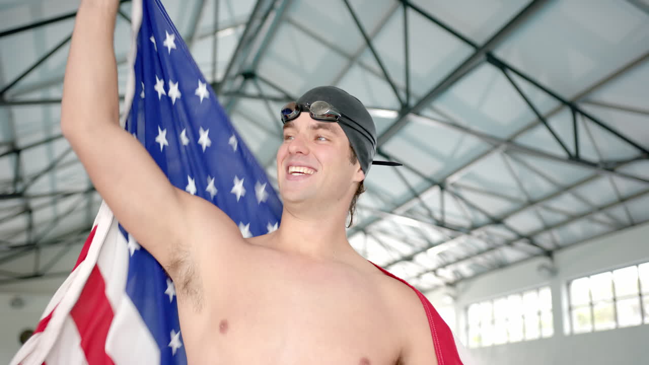 Celebrating victory, Male Swimmer holding American flag and smiling in indoor pool