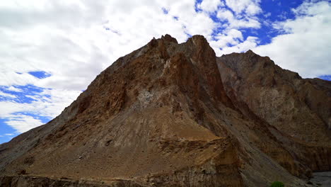 Pan-right-shot-of-a-dry,-dried-out-landscape,-mountains-under-a-huge-white-cloud-on-the-sky