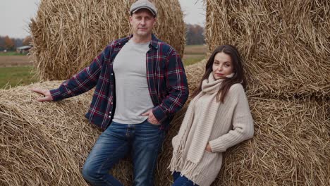 couple posing beside hay bales