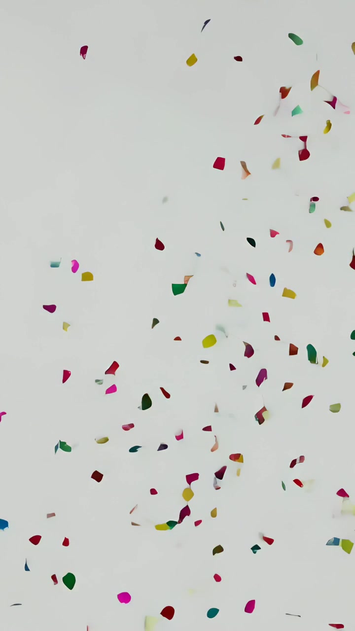 Video verticale: Coriandoli colorati di carta stagnola che cadono su uno sfondo grigio per una celebrazione.