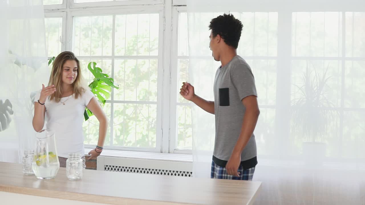 행복한 젊은 부부가 파자마를 입고 부 ⁇ 에서 음악을 듣고 춤을 추는 느린 동작 촬영. 사랑에 빠진 다민족 부부