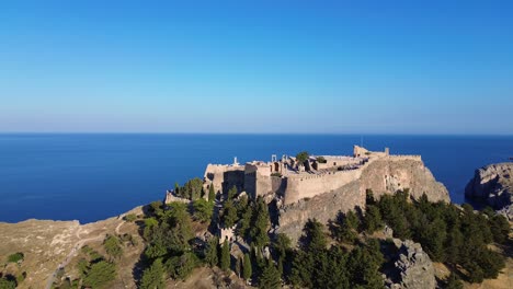 acropolis of lindos in rhodes, greece with houses and mediterranean sea during the day filmed with the drone