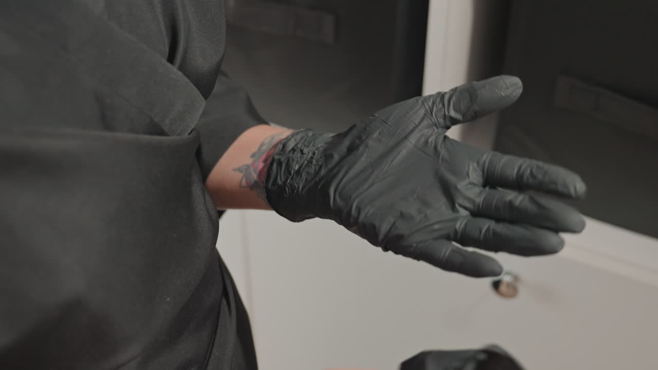 caucasian tattoo artist removing black gloves revealing tattooed wrist and skin, closeup hand inspection, gentle motions, postprocedure care focus, studio background, calm completion and aftercare