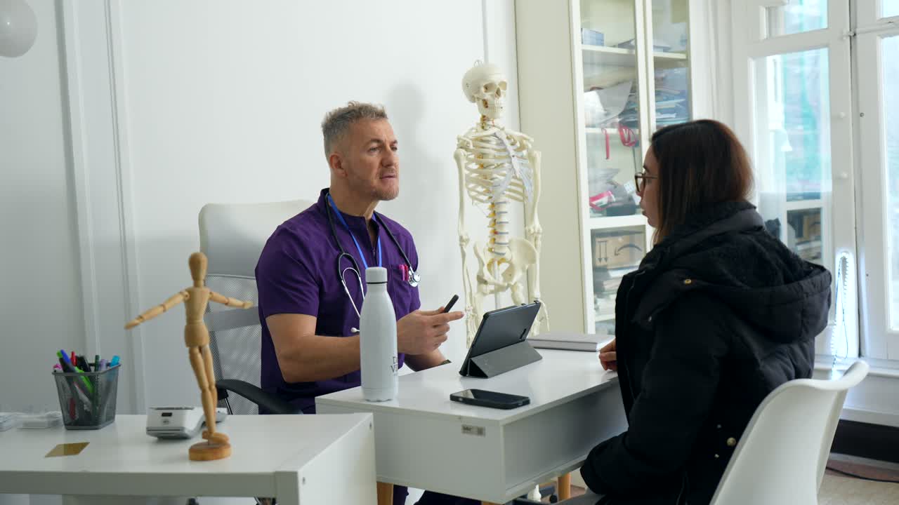 Læge konsulterer med kvindelig patient på et lægekontor.