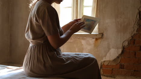 person sitting in a dilapidated room holding an artwork