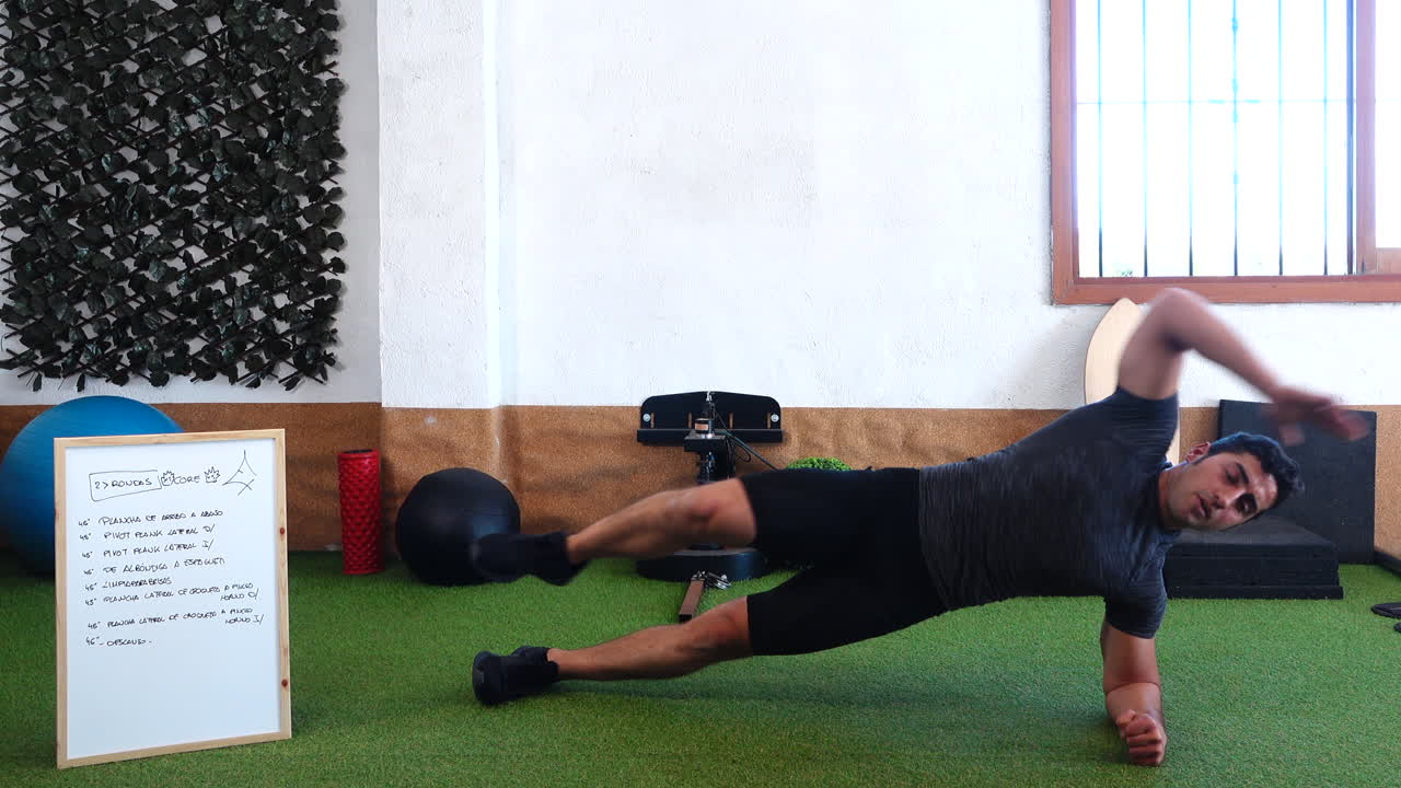 entrenador muscular durante la clase en línea en la que realiza una tabla de ejercicios abdominales
