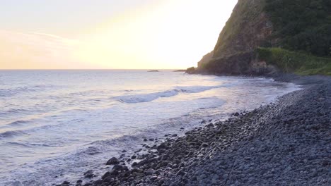cámara lenta, vista de línea baja de las olas rompiendo en una costa rocosa en la isla hawaiana, maui durante la puesta de sol