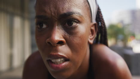 african american woman exercising outdoors taking rest looking ahead in the city