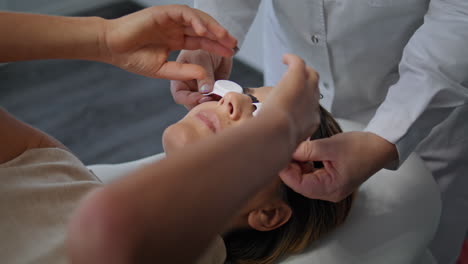 cosmetologist putting protective glasses at woman face in beauty clinic closeup.