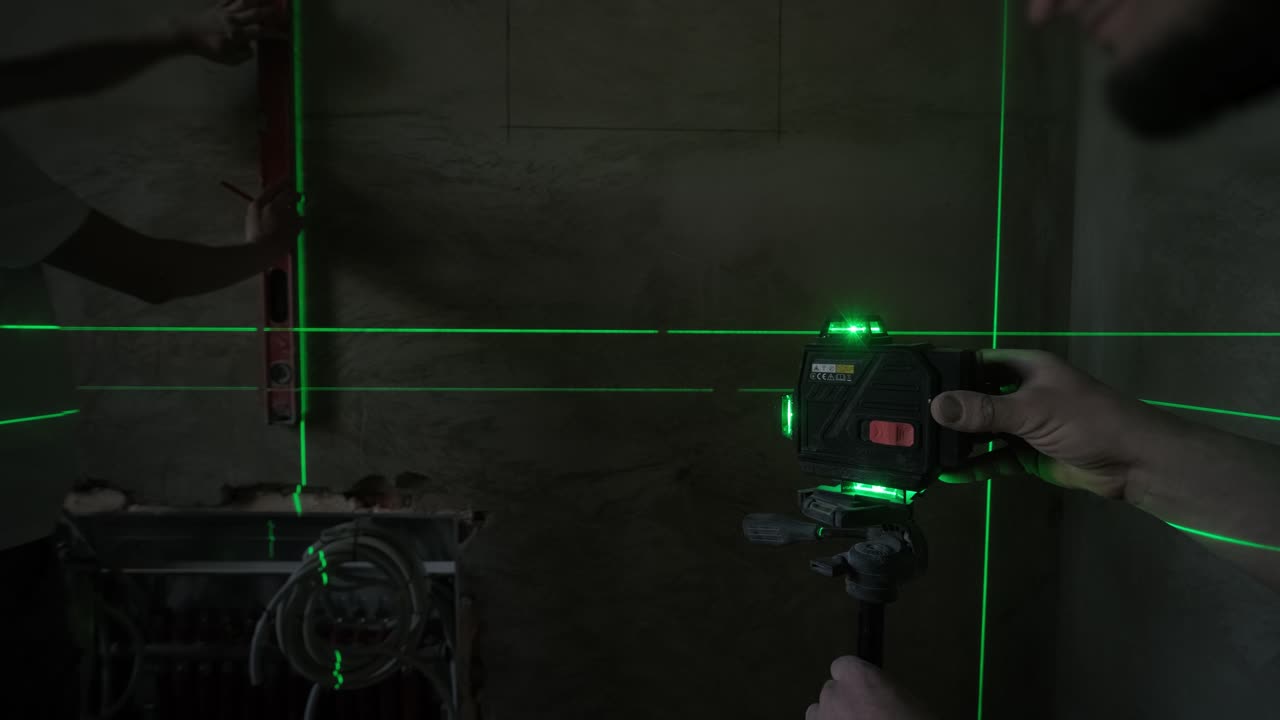 A construction worker uses a laser level to ensure precise alignment on a wall, with visible green laser lines enhancing the accuracy of the work