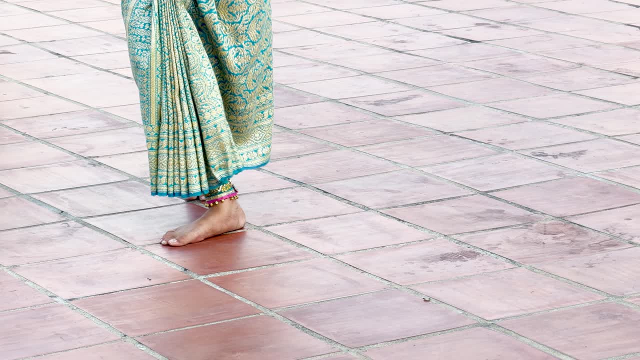 Eine Aufnahme aus der Froschperspektive zeigt eine Tänzerin, die den traditionellen thailändischen Fingernageltanz im Freien aufführt.