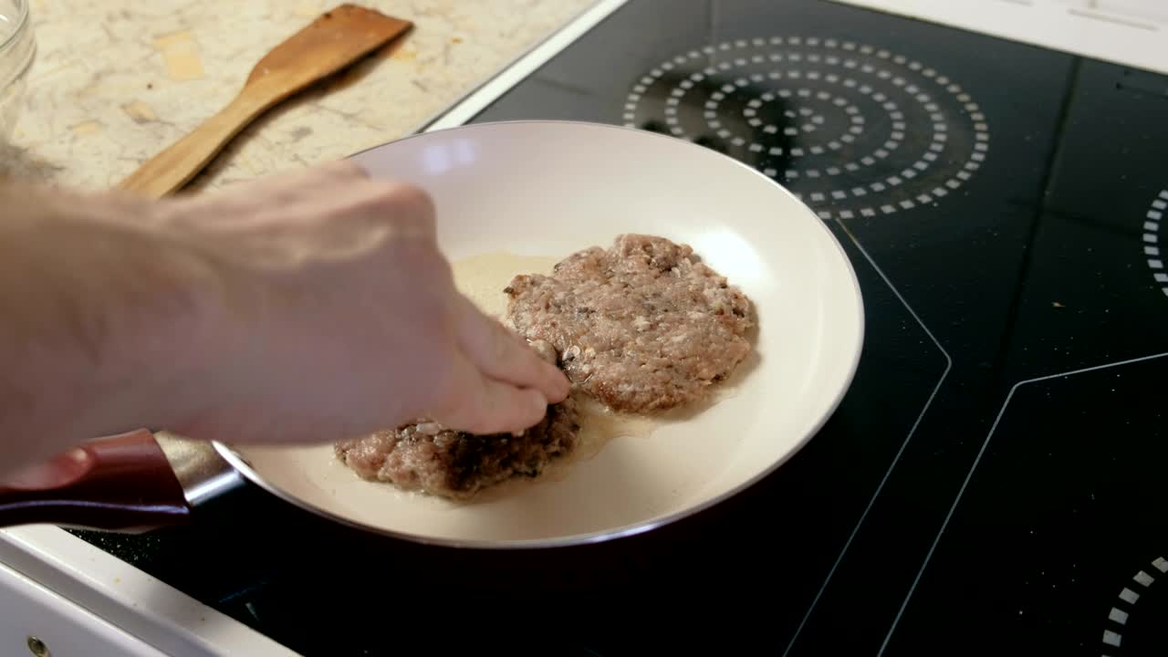한 남자가 햄버거를 위해 팬 코틀에 고 있습니다. 손을 가까이 어보세요.