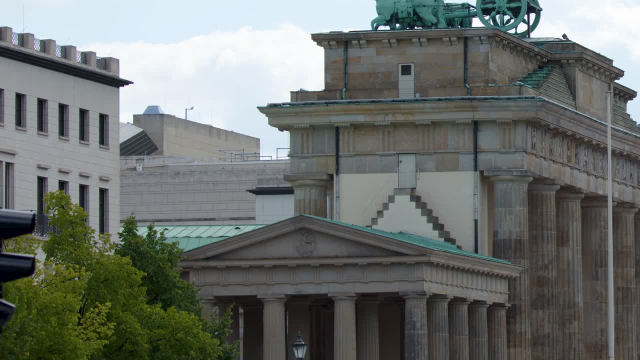 Daytime camera tilt reveals Brandenburg Gate quadriga, neoclassical architecture, urban street, and pedestrians