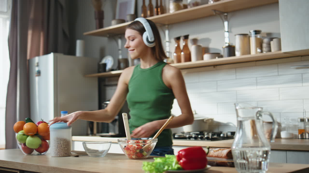 Woman Cooking Salad in Kitchen with Headphones