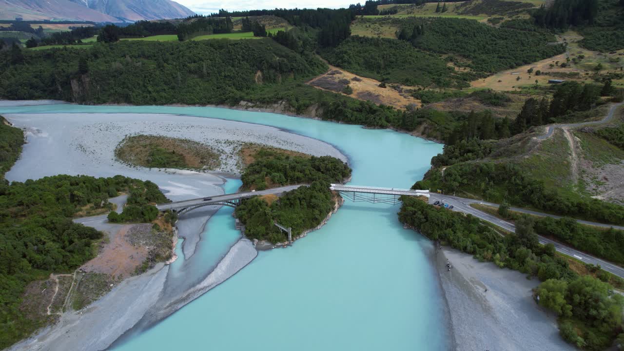Drone shot following a car driving over a bridge at Rakaia River, sunny day in NZ