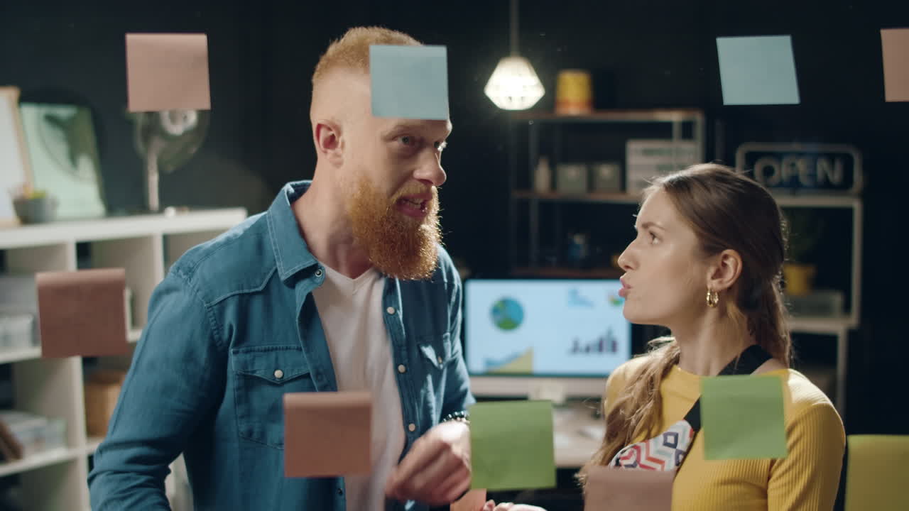 gente de negocios discutiendo sobre pegatinas en la pared transparente en la oficina de hipster