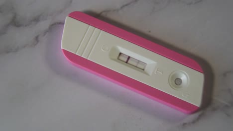 close-up shot of a positive pink pregnancy test on the marble table top