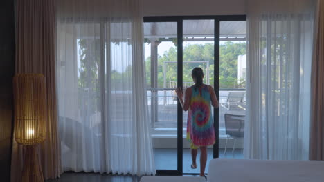 rear of a woman going outside the verandah of a hotel room on renaissance bali uluwatu resort and spa, bali indonesia