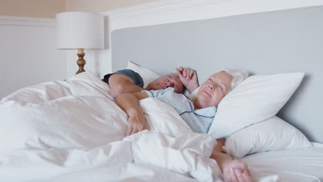 sleeping senior couple lying in bed at home together