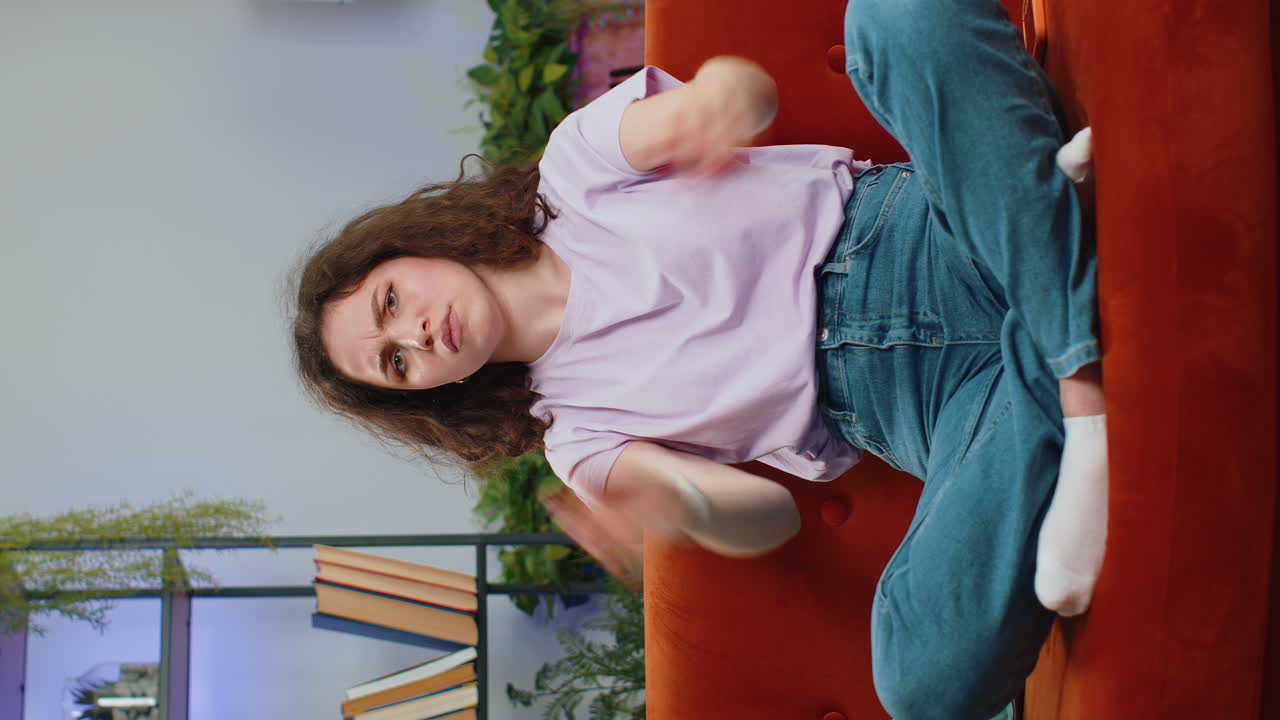 Upset young woman showing thumbs down, dislike bad work, disapproval, dissatisfied feedback at home