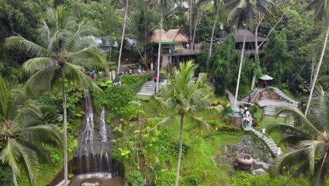 tourists enjoying activities in tropical rainforest amid palm trees, waterfall, rice terraces in alas harum ubud, bali