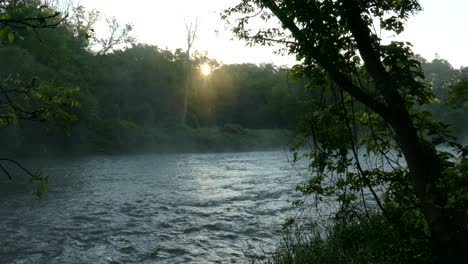 golden setting sun with rising steam across a calmly flowing river