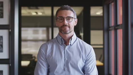 Middle-aged-white-male-businessman-wearing-glasses-looks-up-and-smiles-to-camera,-close-up