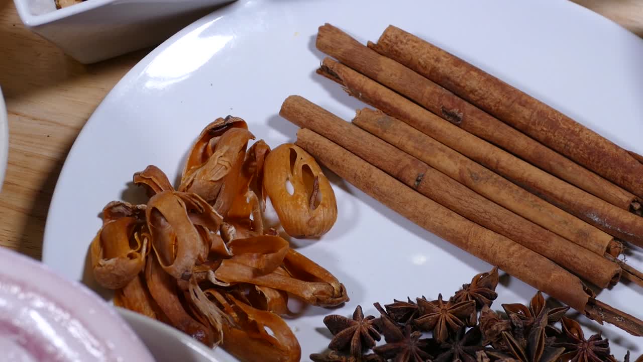 Cannella, anice stellato ed erbe aromatiche su piatto bianco, primo piano