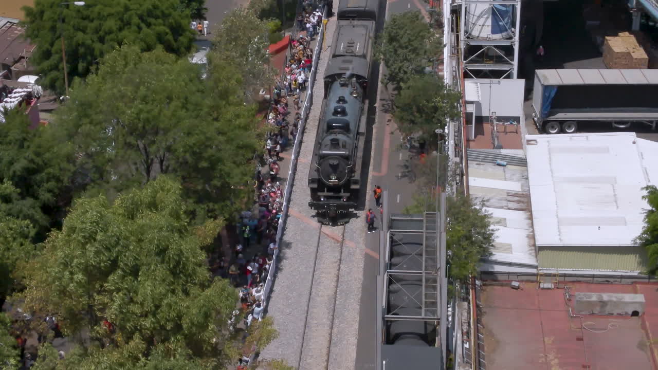 People lining up in elevated road in Mexico city, awaiting the arrival of the historic canadian pacific 2816 Empress steam locomotive for ceremonial Final Spike completing that continental connection