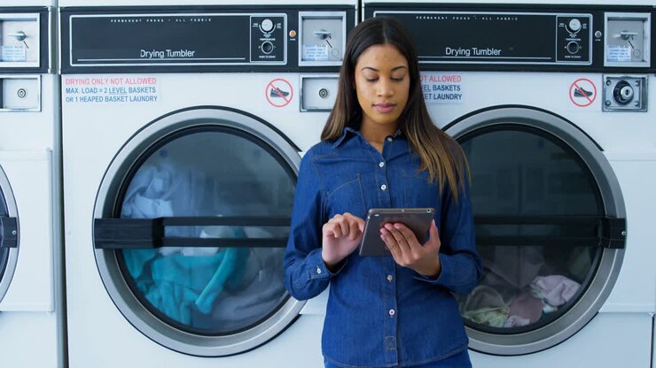 Woman using digital tablet at laundromat 4k