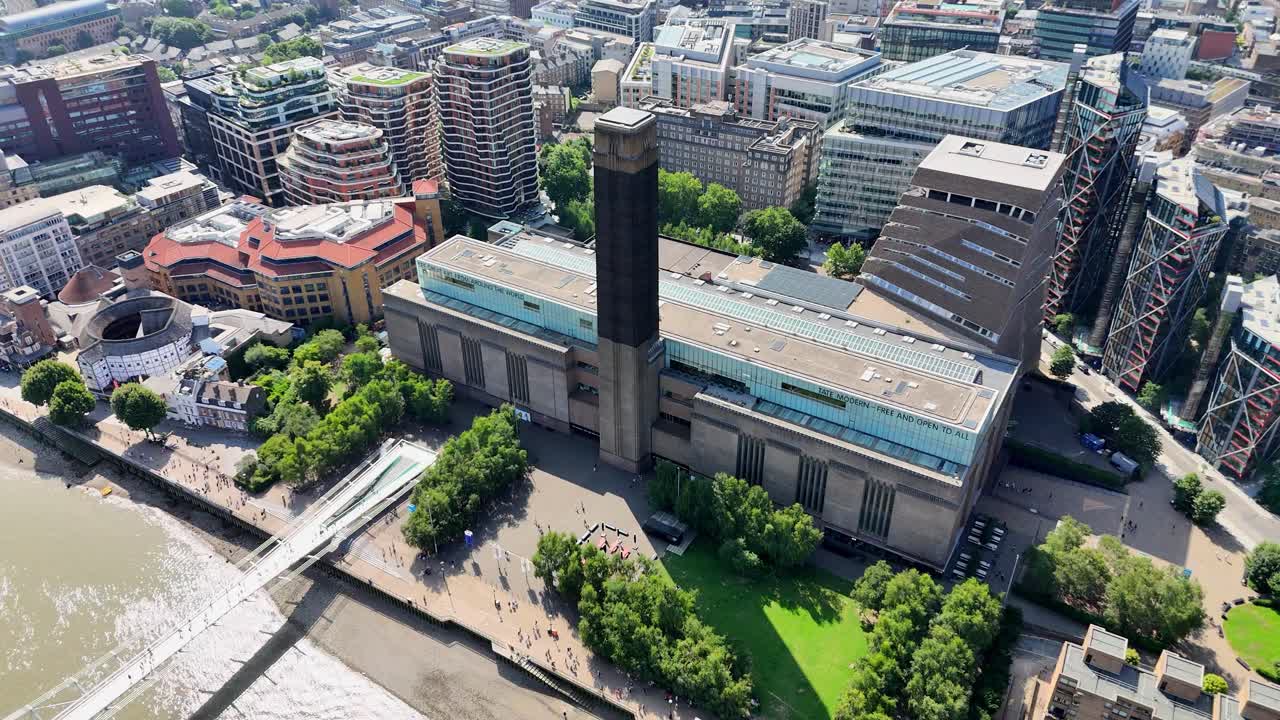 Sweeping aerial pan over Tate Modern, Millennium Bridge, and lush riverside gardens in central London. Captures vibrant Thames views, iconic architecture, and urban greenery in cinematic detail