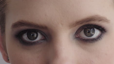 cerrar los ojos de una mujer joven que se abre con maquillaje mirando los cosméticos de belleza de la cámara