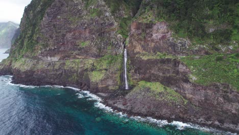épica cascada de acantilado que se derrama en el océano en madeira, portugal dron aéreo 4k dando vueltas tirando hacia atrás
