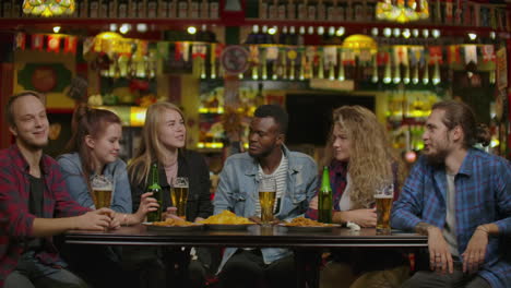 diverse group of friends celebrate with a toast and clink raised glasses with various drinks in celebration. beautiful young people have fun in the stylish bar/ restaurant.