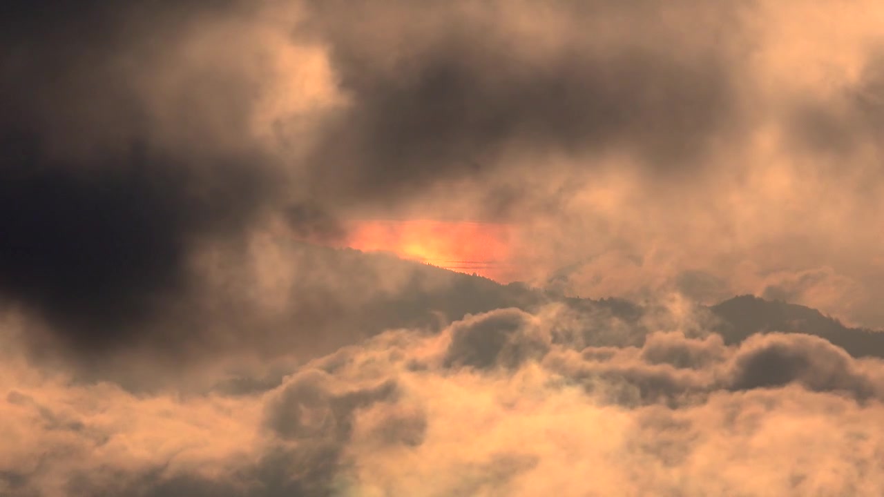 Golden Sunset Light Glowing Behind Dark Mountain Clouds