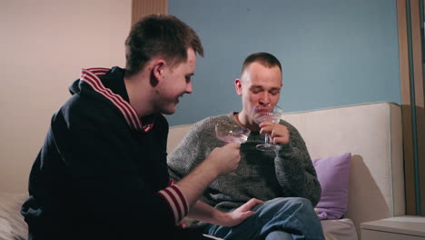 two men celebrating with cocktails in bedroom