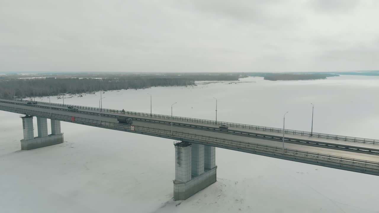 플라이캠은 겨울 강 위에 철탑이 있는 거대한 다리를 촬영합니다.
