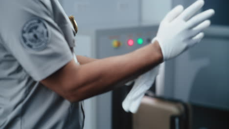 airport security personnel putting on gloves during baggage screening