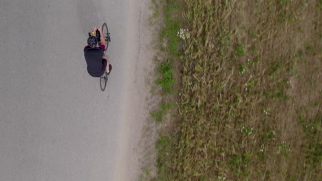 overhead view of a cyclist riding a bike on the roadpassing by on fields