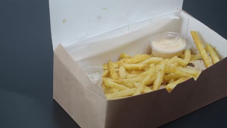 closeup of a box of french fries with sauce, a wrap, and a side of dip