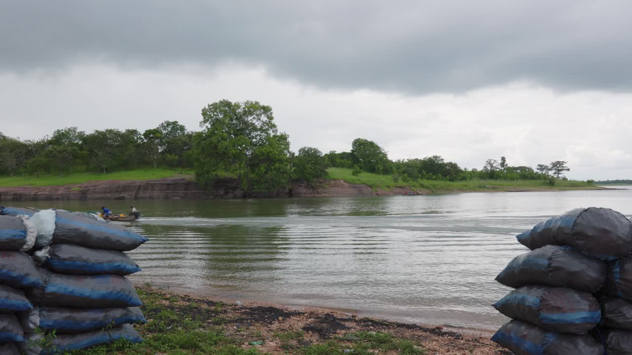 Canoa de pescadores locales con motor fueraborda cruza rápidamente un río.