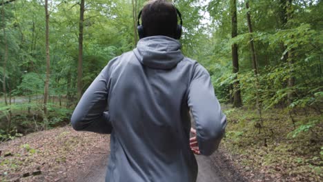 man running through forest wearing headphones
